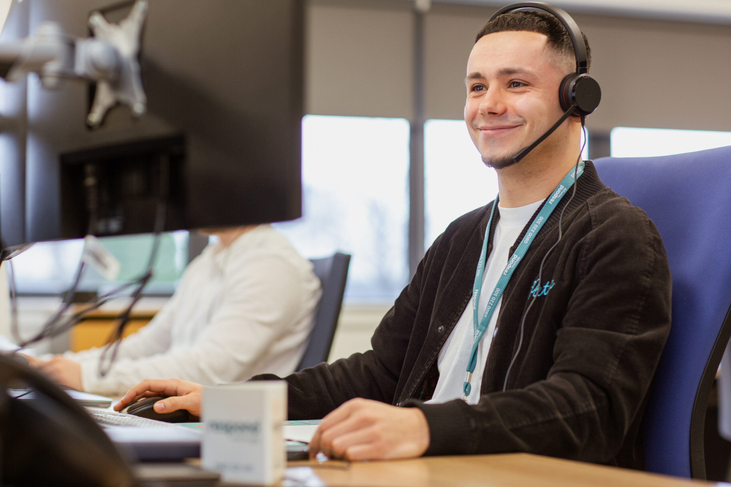 Homepage banner 1 A Respond customer service agent, wearing a headset, smiles at his computer screen