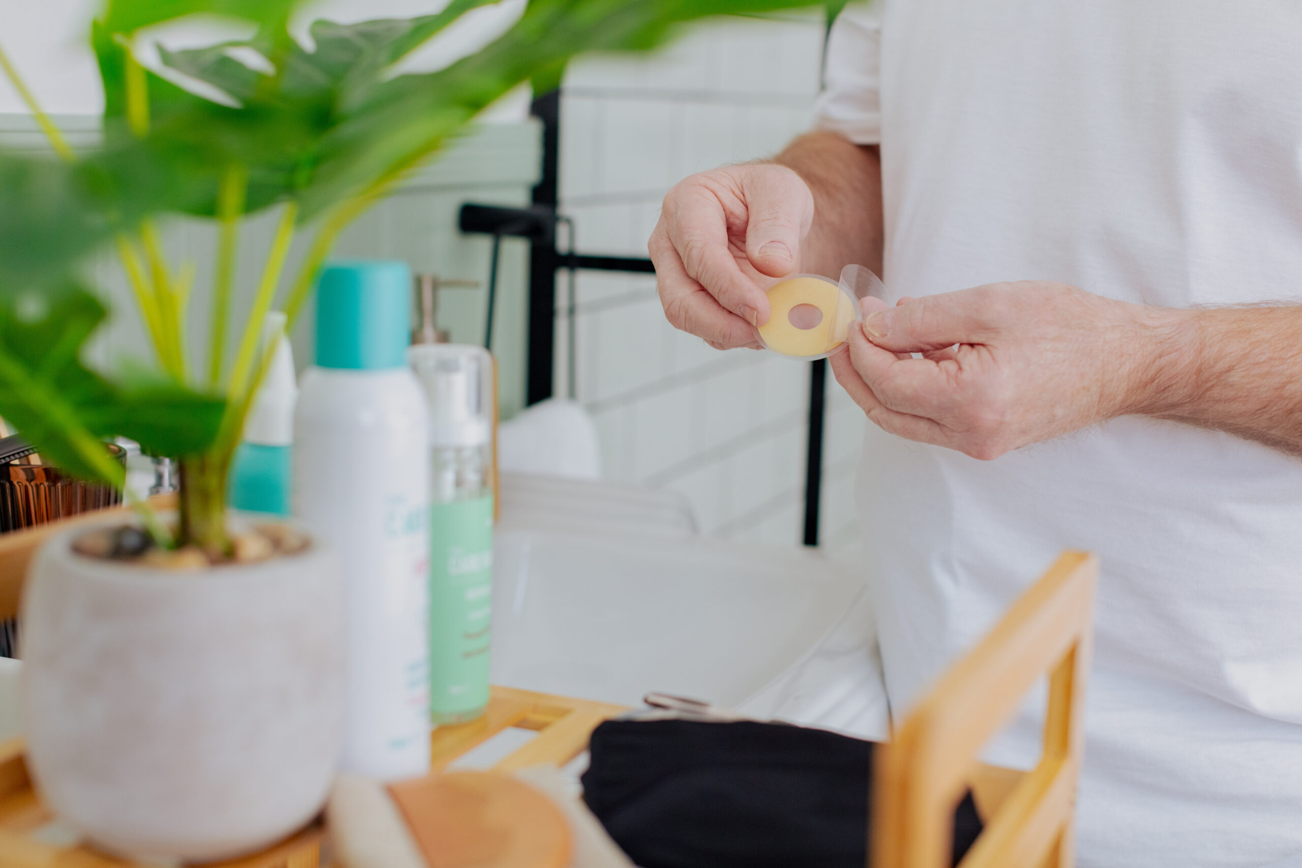 A user unpackages an eakin seal in the bathroom alongside other Respond stoma products.