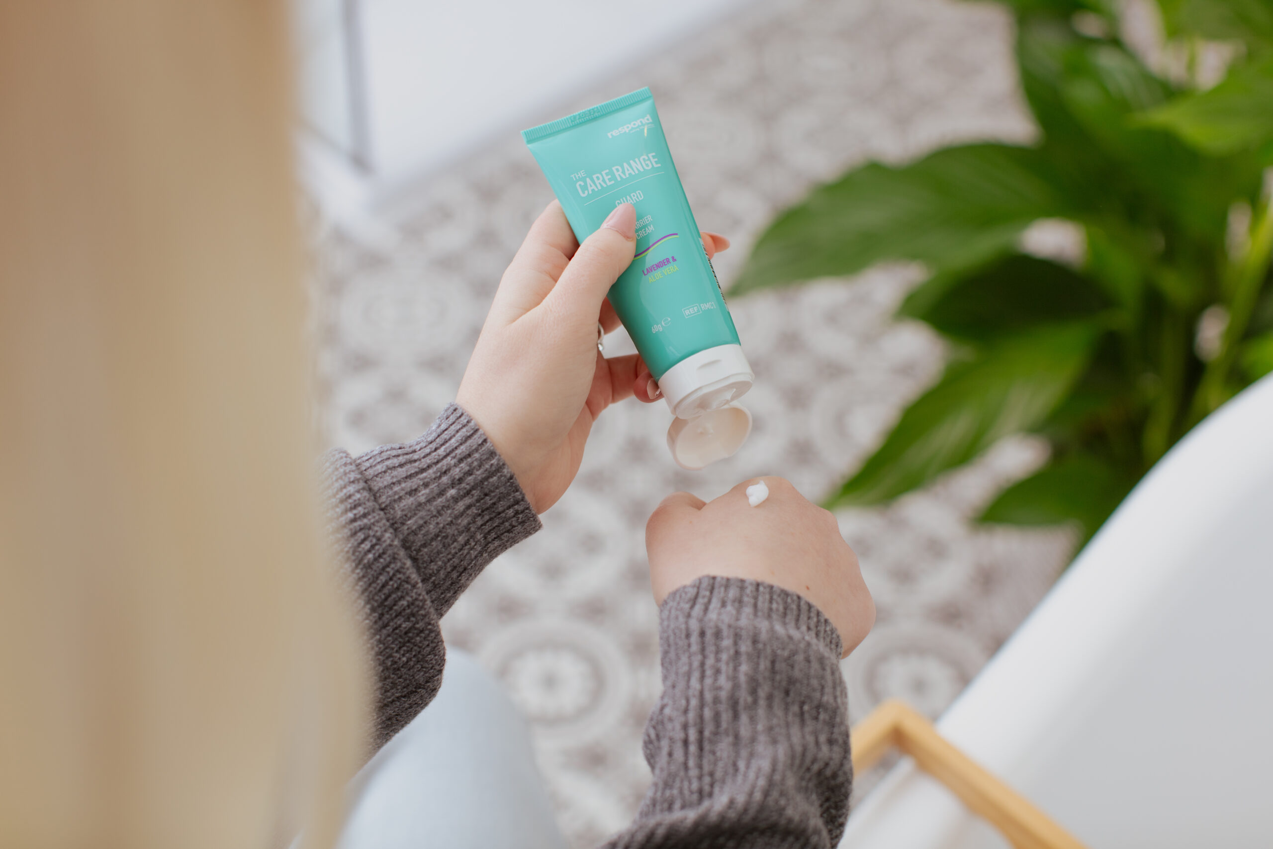 A user squeezes some of our GUARD barrier cream in the scent lavender and aloe vera onto the back of their hand.
